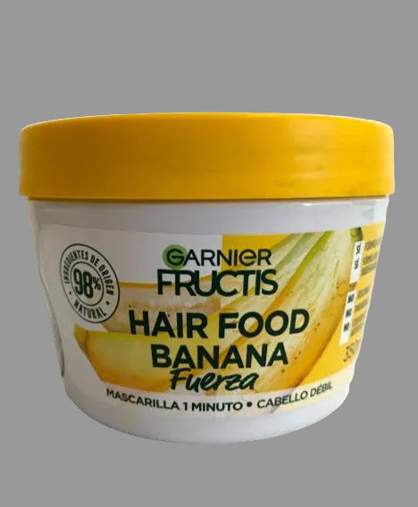 A white plastic jar of Garnier Fructis Hair Food Banana Fuerza hair mask with a bright yellow lid, shown against a plain white background.